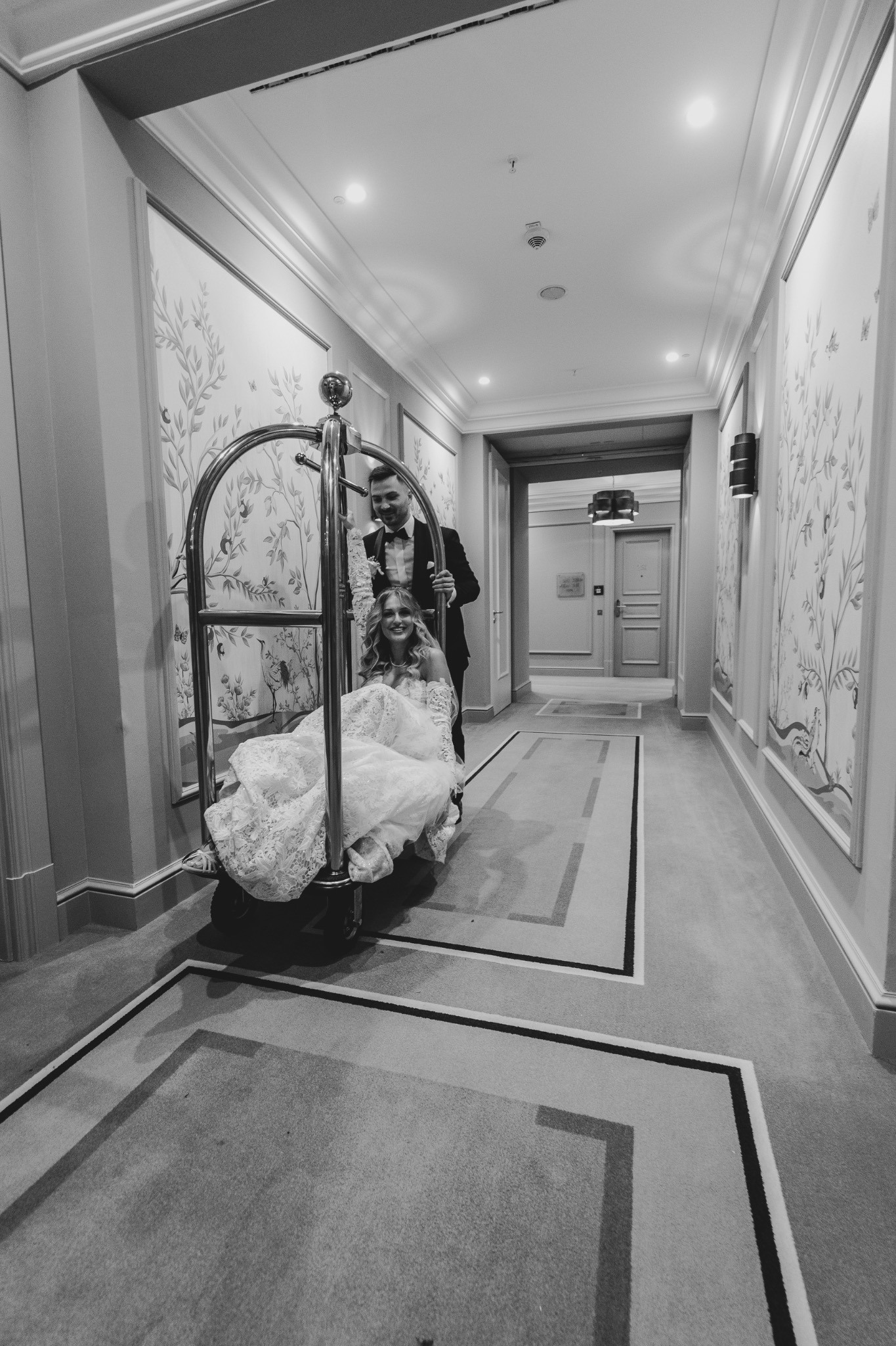 Christine auf einem Gepäckwagen im Hotelflur, Schwarz-Weiß