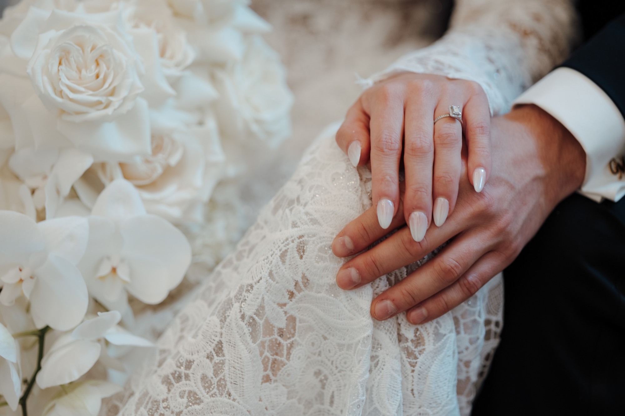 Ihre Hände liegen ineinander auf dem Brautkleid